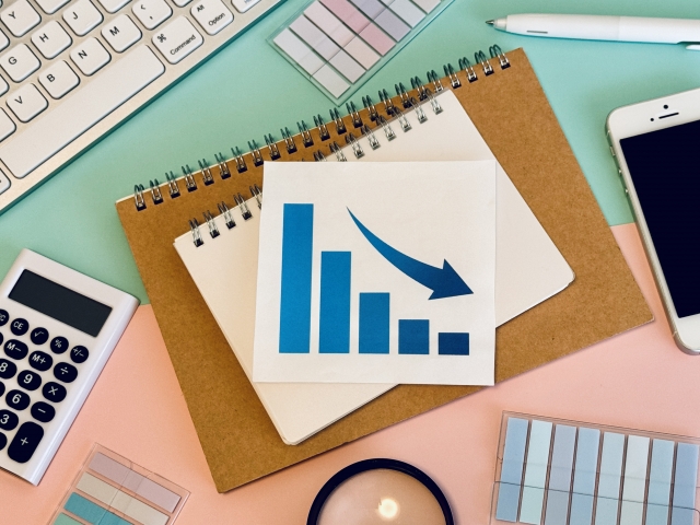 下向きの矢印と棒グラフが描かれた紙